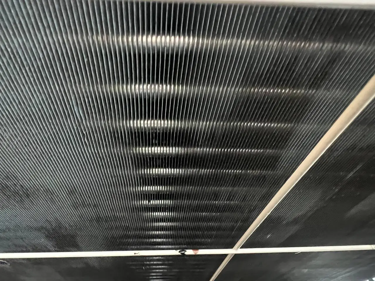 Close-up of condenser coil fins, straight and evenly spaced, catching the light.