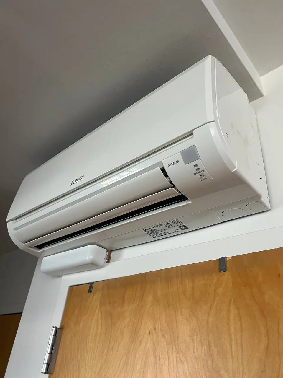 Wall-mounted ductless indoor unit seen from below, factory spec labels still on the casing.
