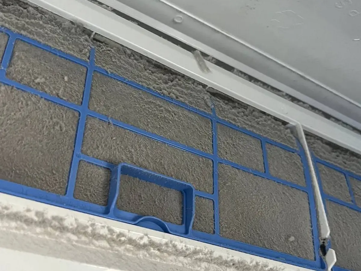 Mini-split intake filter caked with a solid grey layer of dust.