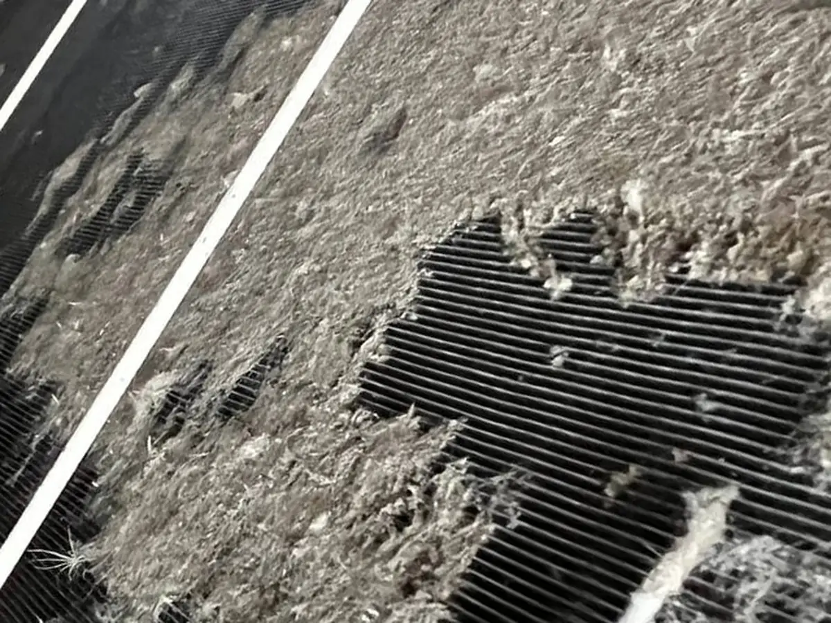 Outdoor condenser coil buried under a thick grey mat of lint and dust.