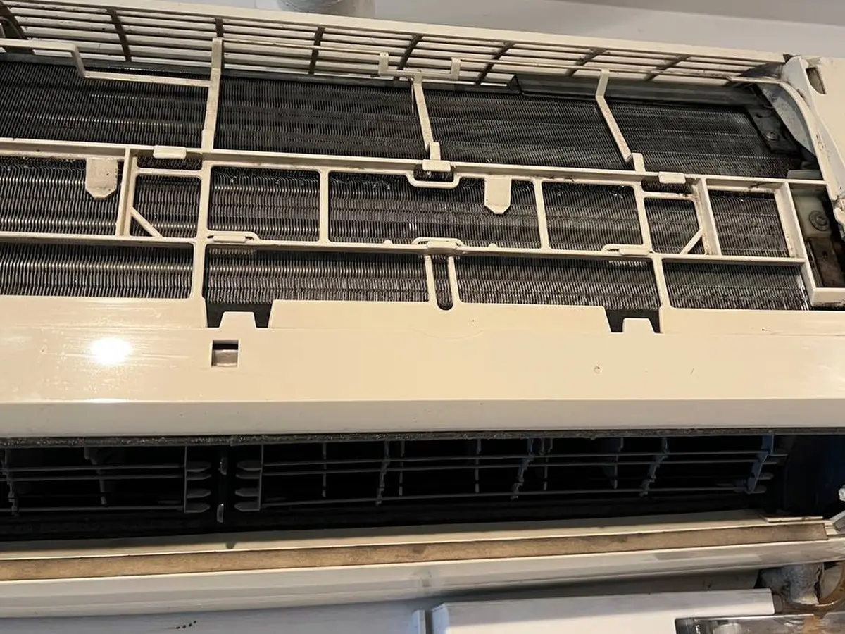 The cleaned unit reassembled on the wall, guard grille back in place.