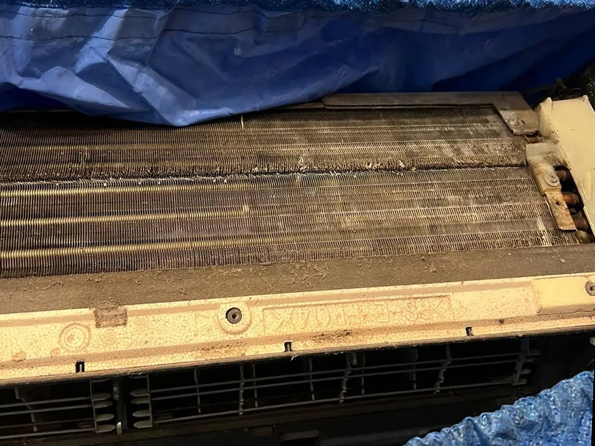 Coil fins clogged with dark grime, the unit wrapped in a wash bag.