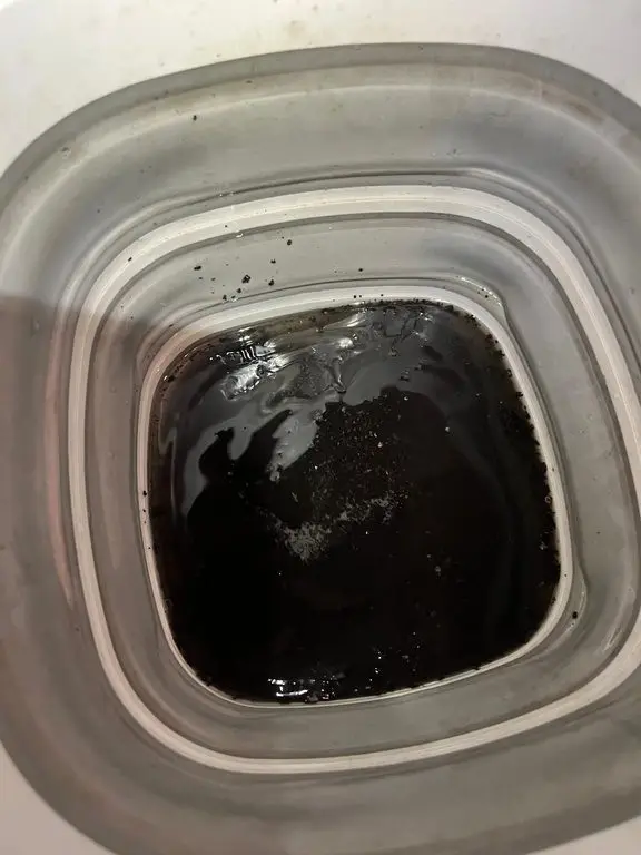 A bucket of near-black rinse water drained from an air conditioning unit.